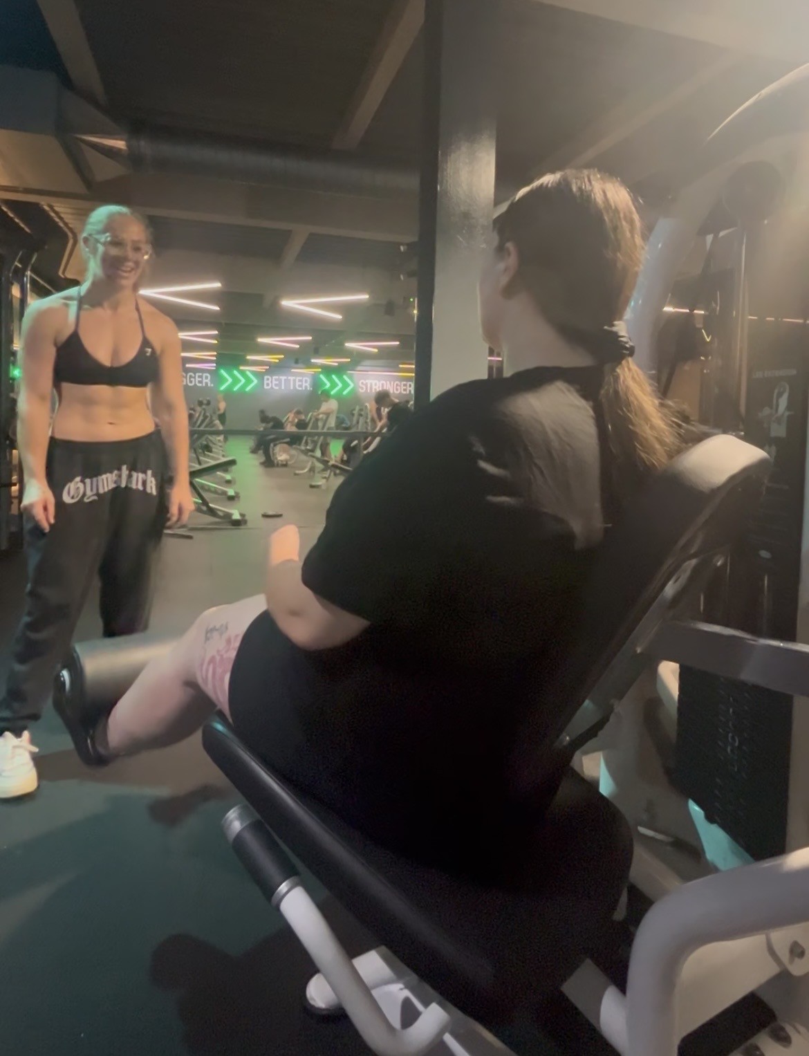 Client working through leg extensions while Charlotte coaches