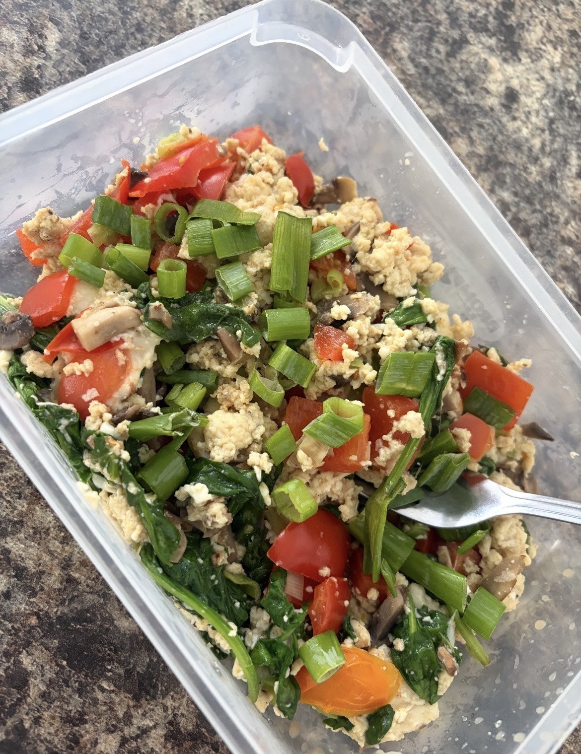 A client's meal prep — egg scramble with spinach, tomatoes and spring onions